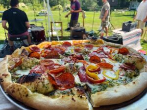 Farm Fest at White Gate showing a pizza with musicians in the background.